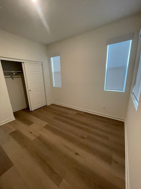 Bedroom with wood-look flooring and closet