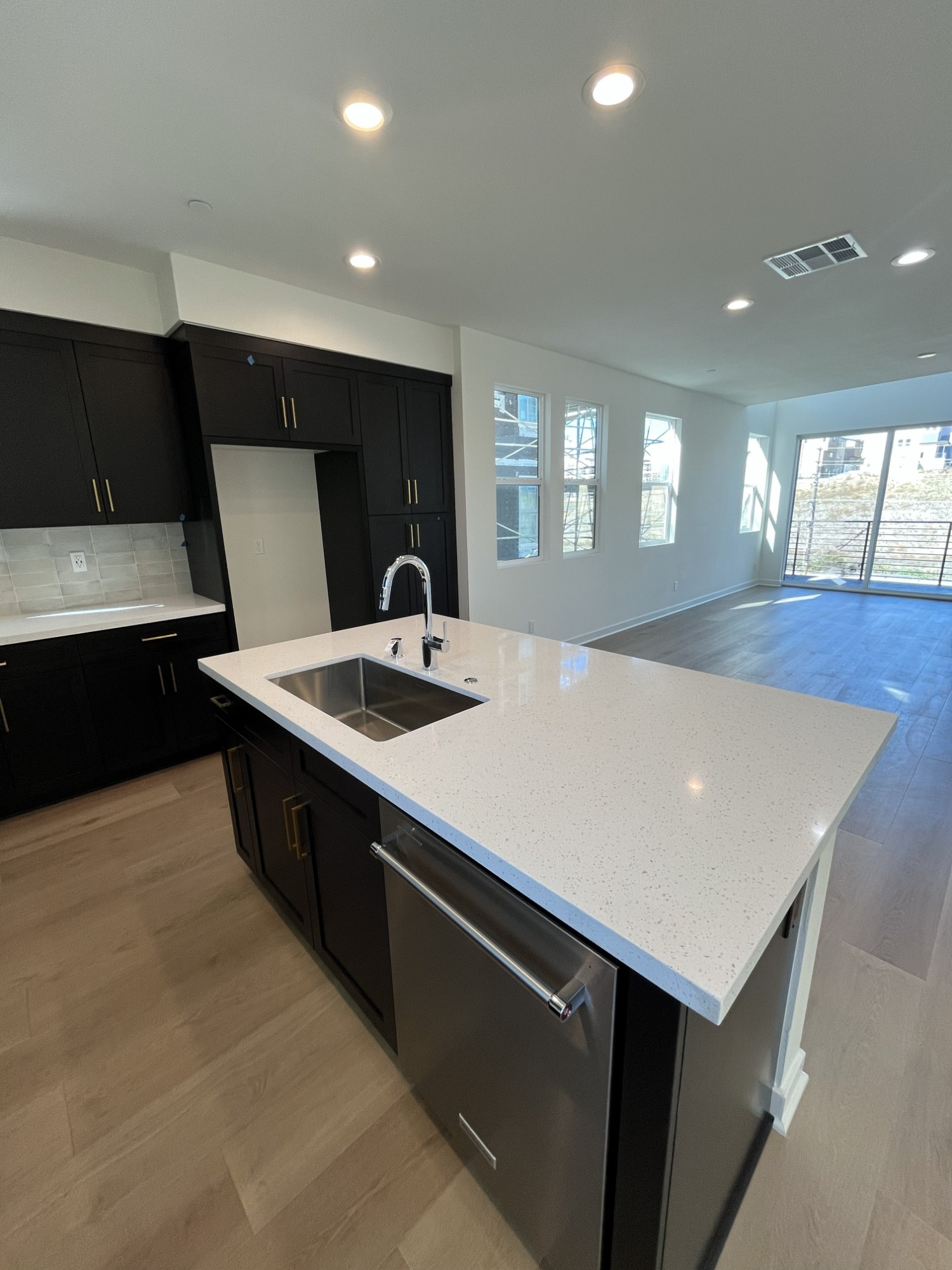Kitchen island opening onto a bright living room with balcony