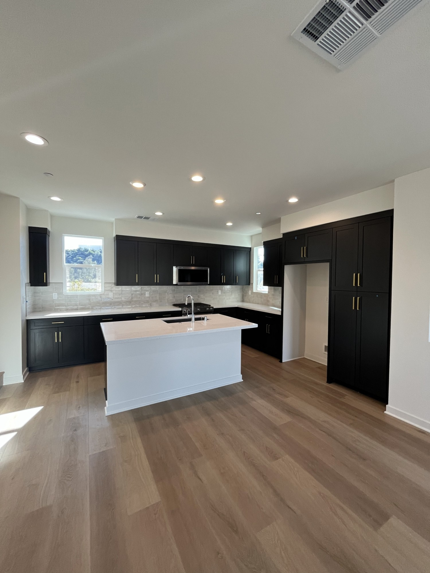 Finished kitchen with dark shaker cabinets, brass hardware and a white island